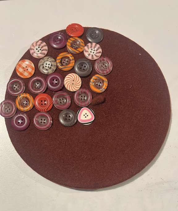 Deep brown felt beret decorated with assorted multicolor buttons in autumn tones